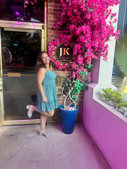 Jenn at the JK by Chef King entrance surrounded by pink flowers