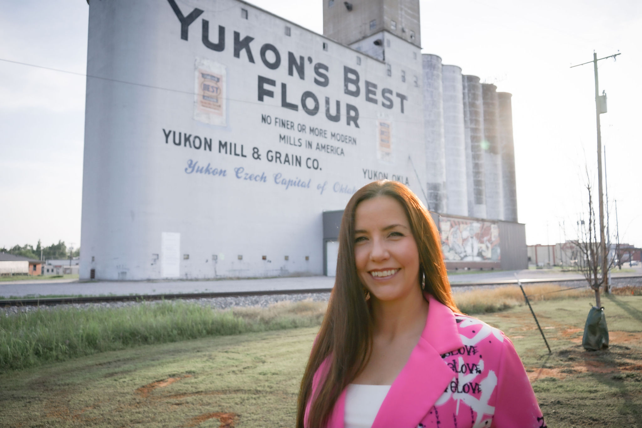 Jenn Howard in a pink jacket in front of the historic Yukon’s Best Flour Mill in Yukon, Oklahoma